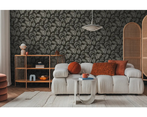 Wohnzimmer mit Sofa, Beistelltisch und Regal vor einer mit Blättern gemusterten Tapete