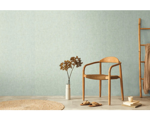 Wohnraum mit gemusterter Tapete, Holzstuhl und Deko-Elementen für ein helles Ambiente