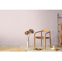 Dekorative Wohnrauminszenierung mit Stuhl, Teppich, Dekoration und Bambusleiter vor einer Wand.