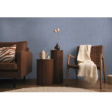 Wohnzimmer mit Sofa, Sessel und Beistelltischen vor einer blauen Wand