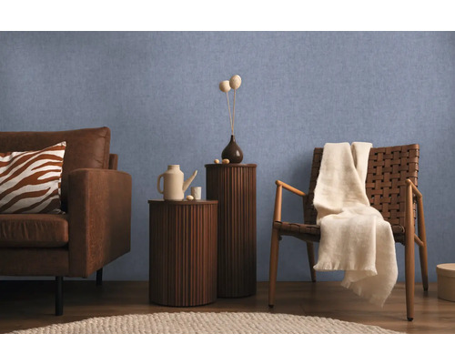 Wohnzimmer mit Sofa, Sessel und Beistelltischen vor einer blauen Wand