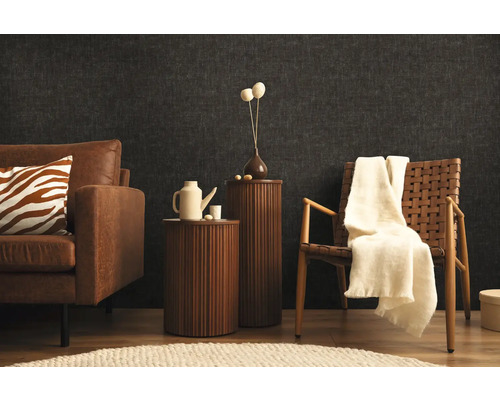 Wohnzimmer mit Sofa, Sessel und Beistelltischen vor einer dunklen Wand