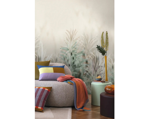 Wohnzimmer mit Sofa, Kissen, Decke und Pflanzenmotiv-Tapete