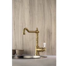 Goldfarbene Küchenarmatur mit weißem Griff montiert in einer Spüle