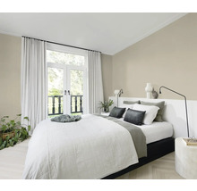 Helles Schlafzimmer mit Bett, Nachttischen und Vorhängen vor einer Balkontür