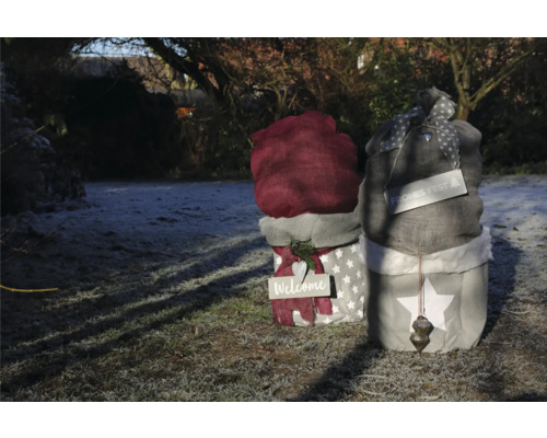 Dekorative Stofffiguren im Garten mit den Aufschriften Willkommen und Frohes Fest.