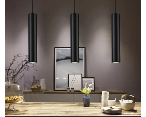 Drei schwarze Pendelleuchten über einem Tisch in einem Esszimmer.