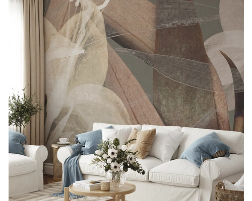 Wohnzimmer mit abstraktem Blättermuster an der Wand hinter einem weissen Sofa.