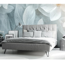 Schlafzimmer mit Bett, Nachttisch und dekorativer Blumendarstellung an der Wand.