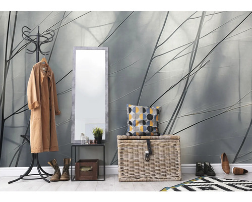 Eingangsbereich mit Garderobenständer, Spiegel und Aufbewahrungskorb vor einer Tapete mit Pflanzenmotiven.