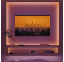 Wohnzimmer mit Fernseher, Regalen und indirekter Beleuchtung für eine gemütliche Atmosphäre