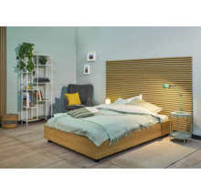 Schlafzimmer mit Bett, Nachttisch, Lampe, Sessel und Bücherregal