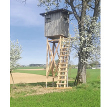 Hochsitz aus Holz auf einer Wiese mit Feldern im Hintergrund