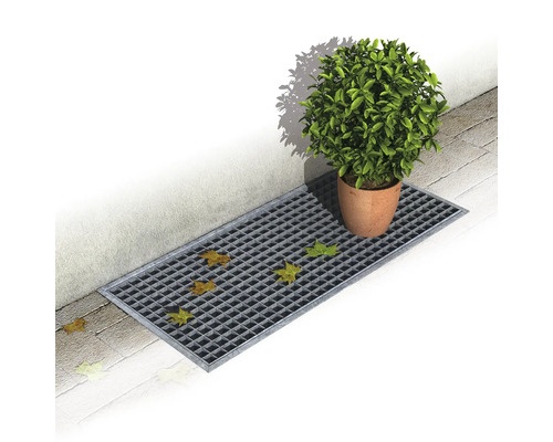 Gitterrinne mit Laub und einem Blumentopf auf Pflastersteinen