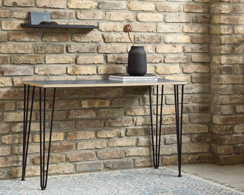 Tisch mit Haarnadelbeinen vor einer Backsteinmauer
