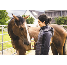 Frau hält Ballistol Animal Tierpflegeöl neben Pferd