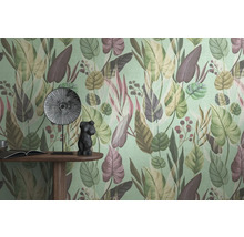 Detailaufnahme einer Wand mit einer Tapete mit Blättermuster, einem Tisch mit einem Buch, einer Dekofigur und einem Teller.