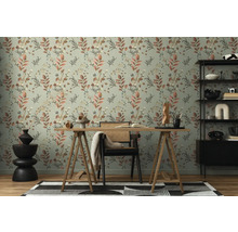 Ein Arbeitszimmer mit einem Schreibtisch vor einer Wand mit floral gemusterter Tapete.