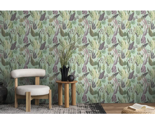 Ein Zimmer mit einer gemusterten Tapete mit Blättern, einem Stuhl und einem Beistelltisch.
