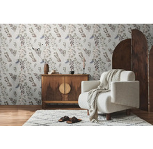 Wohnzimmer mit floraler Tapete, Holzkommode, Sessel und Teppich für eine gemütliche Atmosphäre.