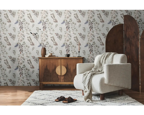 Wohnzimmer mit floraler Tapete, Holzkommode, Sessel und Teppich für eine gemütliche Atmosphäre.