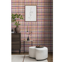 Wohnzimmer-Interieur mit karierter Tapete, Kommode, Hocker und Dekorationen für eine gemütliche Atmosphäre.