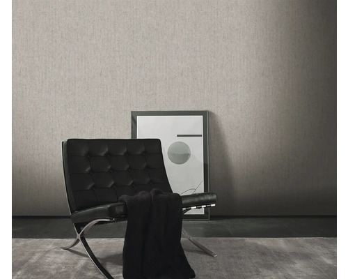 Wohnraum mit einer grauen Struktur-Tapete, einem schwarzen Sessel und einem gerahmten Bild