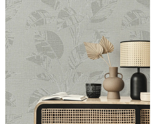 Szene mit einer Wandtapete mit Pflanzenmuster, einem Tisch, einer Lampe, einer Vase und einem Buch.