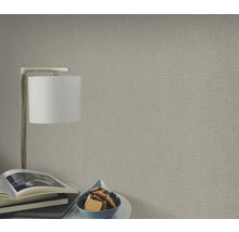 Nahaufnahme einer strukturierten Tapete in einem Wohnraum mit Lampe und Dekoration.