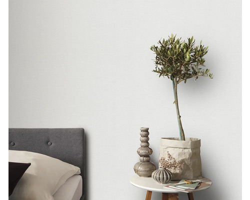 Helles Schlafzimmer mit Bett und Nachttisch mit Dekoration und Pflanze