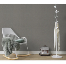 Wohnzimmer mit Schaukelstuhl, Garderobe und Rucksack vor einer grauen Wand