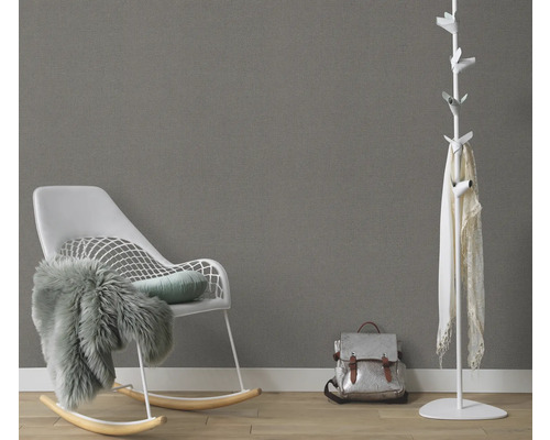 Wohnzimmer mit Schaukelstuhl, Garderobe und Rucksack vor einer grauen Wand