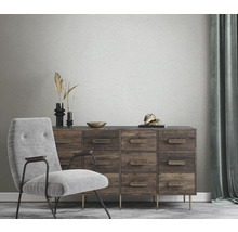 Wohnzimmer mit Sessel, Kommode und floral gemusterter Tapete