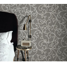 Schlafzimmer mit gemusterter Tapete, Nachttisch, Lampe und Radiowecker