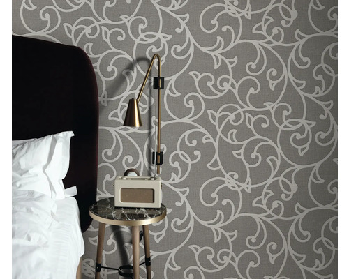 Schlafzimmer mit gemusterter Tapete, Nachttisch, Lampe und Radiowecker