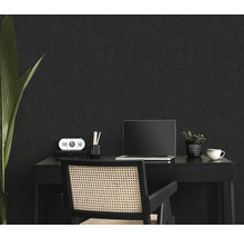 Arbeitsplatz mit Schreibtisch, Stuhl, Laptop und Dekoration vor dunkler Wand