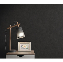 Nachttisch mit Lampe und Bilderrahmen vor dunkler Wand