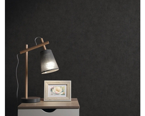 Nachttisch mit Lampe und Bilderrahmen vor dunkler Wand