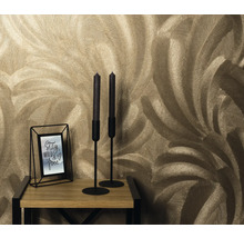 Nahaufnahme einer Wand mit Feder-Tapetenmuster, einem Kerzenständer und einem Bilderrahmen auf einem Holztisch