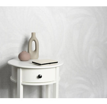 Helle Tapete mit Muster hinter einem weißen Nachttisch mit Dekoration