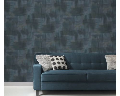 Gemusterte Tapete hinter einem blauen Sofa mit Kissen