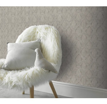 Dekoratives Zimmer mit gemusterter Tapete und Stuhl mit Kissen und Dekofigur