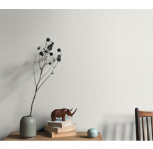 Wandgestaltung mit Pflanzendekoration, Bücherstapel und Holzfigur