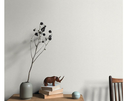 Wandgestaltung mit Pflanzendekoration, Bücherstapel und Holzfigur