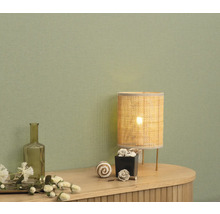 Dekoratives Interieur mit Tischlampe und Accessoires auf einer Kommode vor einer Wand.