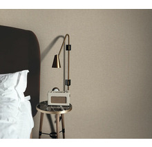 Schlafzimmerszene mit Textiltapete, Nachttisch und Lampe