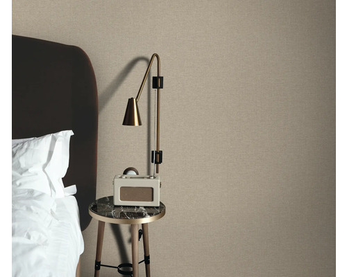 Schlafzimmerszene mit Textiltapete, Nachttisch und Lampe