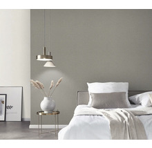 Schlafzimmer mit Bett, Nachttisch, Lampe und grauer Tapete