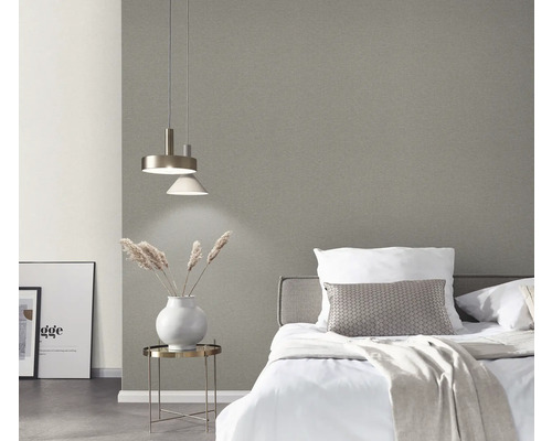 Schlafzimmer mit Bett, Nachttisch, Lampe und grauer Tapete