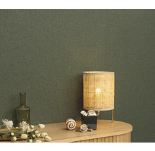 Nahaufnahme einer grünen Textiltapete mit Tischlampe und Dekoration